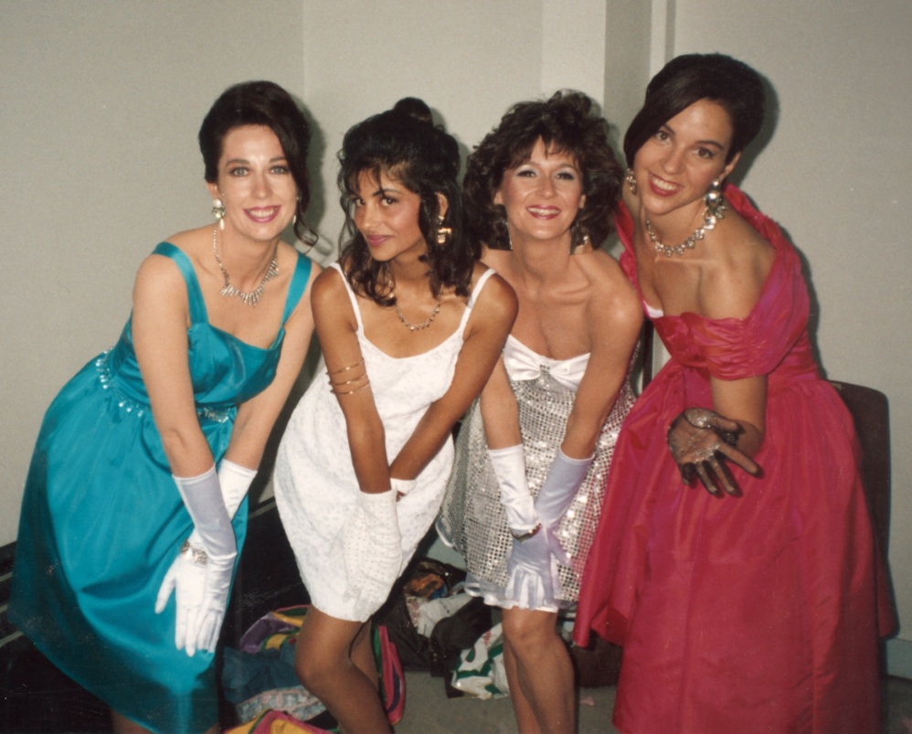 A picture of four young women in fancy dress smiling and posing for the camera